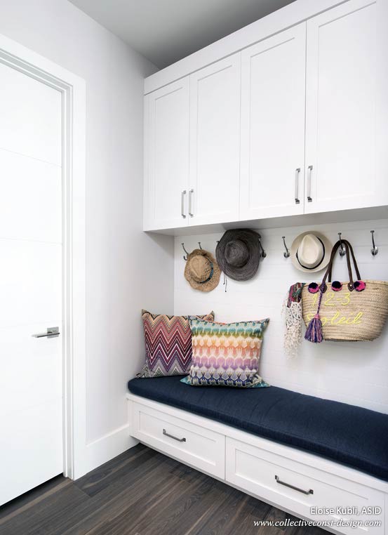 Offering storage above and below, this transitional space helps with organization. Featuring a supple cushion on the bench and white cabinetry throughout, the mud room is directly adjacent to the wet bar and laundry room. Cabinetry: KitchenWorks