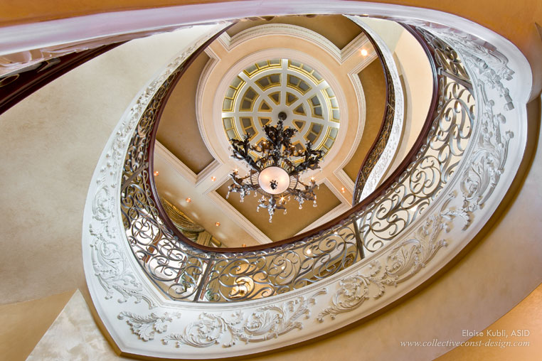 A custom metal stair rail in the center of a curved staircase creates visual drama. A wood handrail adds to the beauty.