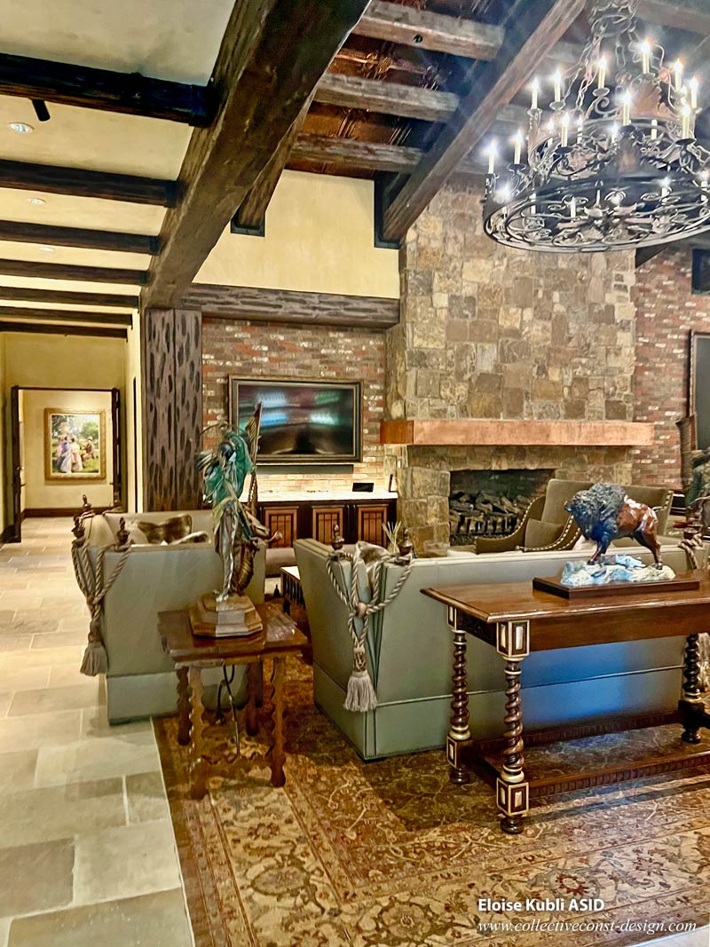 Great room fireplace seating area, chandelier, finished brick walls, and flagstone floors.